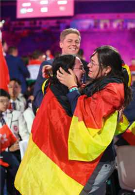 Emotionen die verbinden: Anna Telle (Disziplin Gesundheits- und Sozialbetreuung) und Kim Bücholdt (Disziplin Floristi*in) unter dem zufriedenen Blick von Mentaltrainer Dr. Tom Kossak.