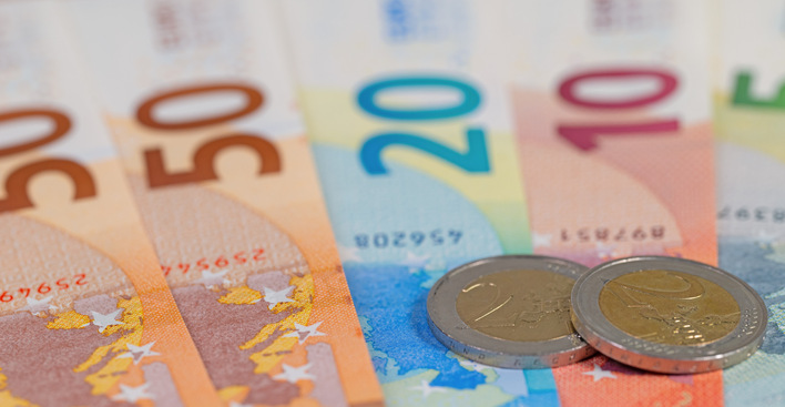 Auf einer Fläche angeordnete Euro-Banknoten und zwei Euro-Münzen. - © M. Schuppich - stock.adobe.com
