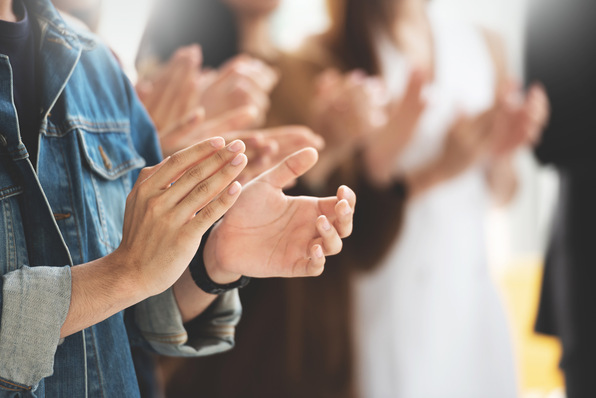 Applaudierende Menschen, Fokus auf die Hände. Gemischte Gruppe in Freizeitkleidung steht in einem hellen Raum. - © eggeeggjiew - stock.adobe.com