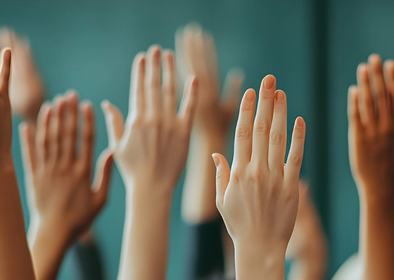 Mehrere erhobene Hände verschiedener Personen, die sich vor einem unscharfen, blaugrünen Hintergrund in die Höhe strecken. - © (Bildquelle: Gustav — stock.adobe.com)